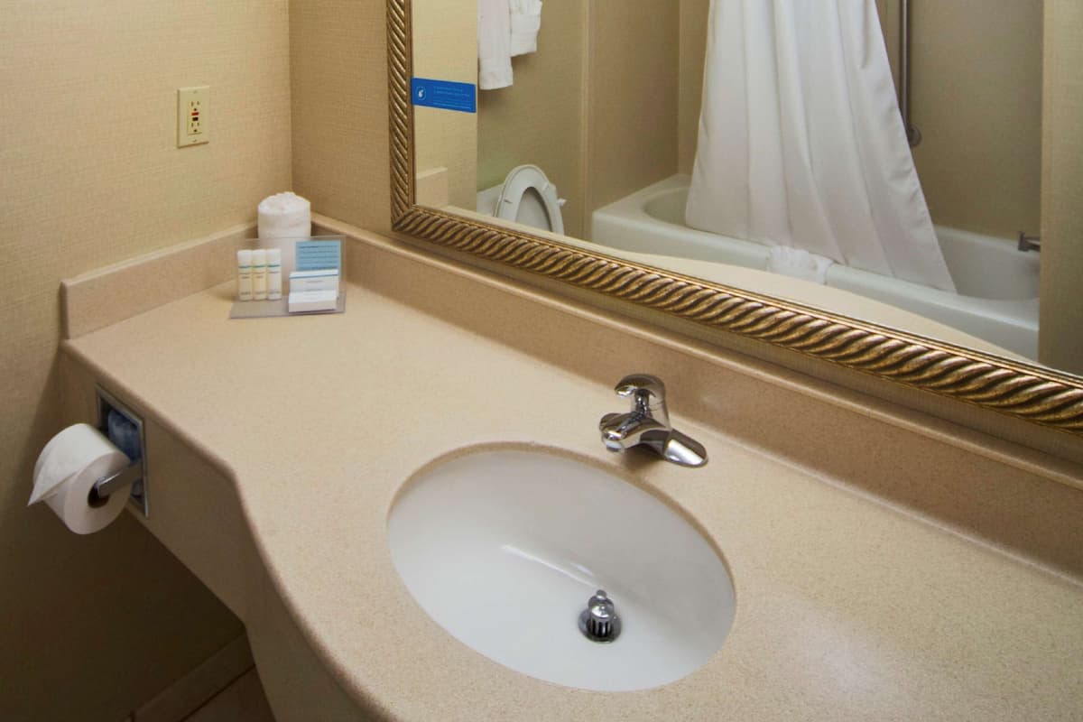 A bathroom with a sink, mirror, and a shower curtain.