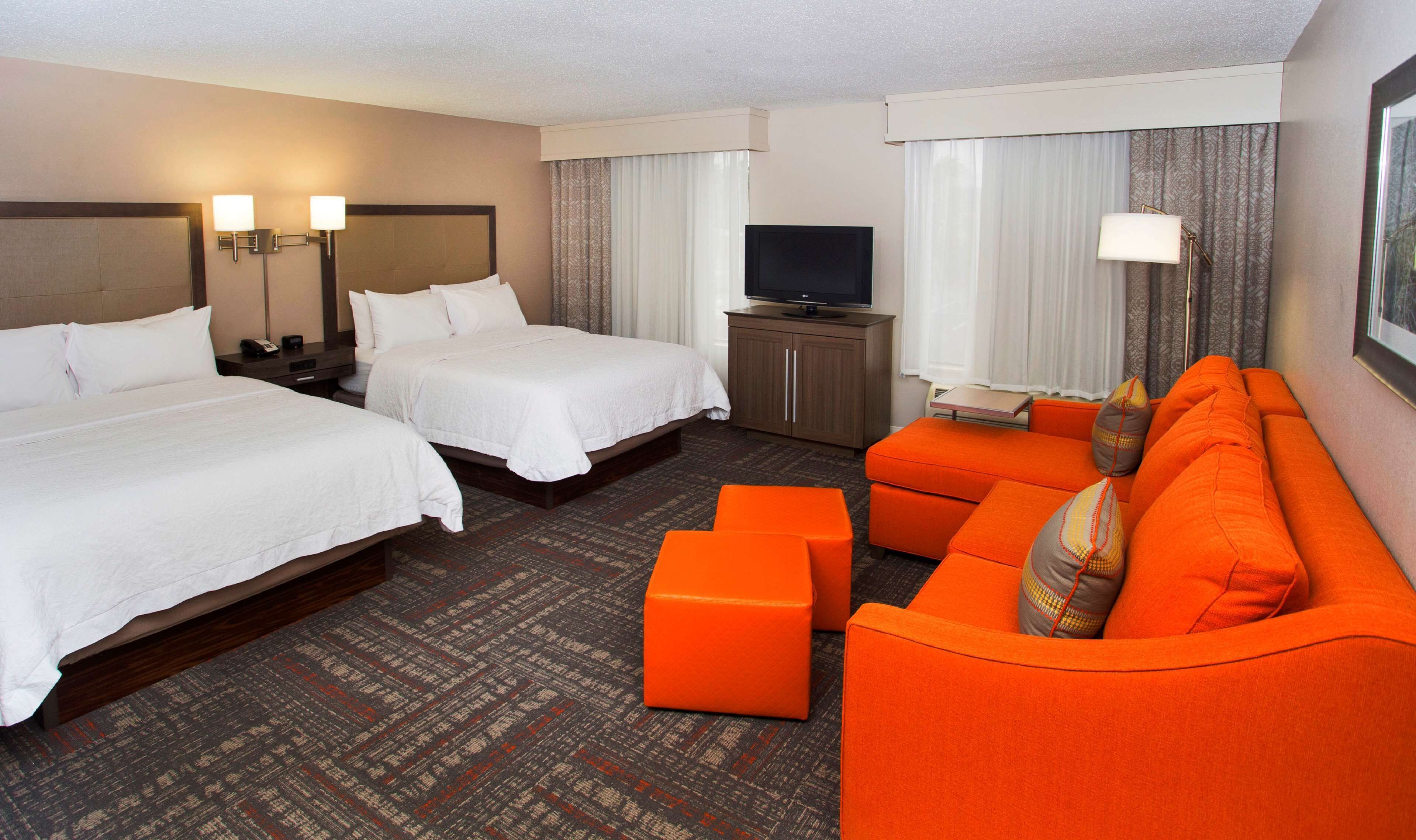 Habitación de hotel con dos camas, televisor, sofá y una mesita.