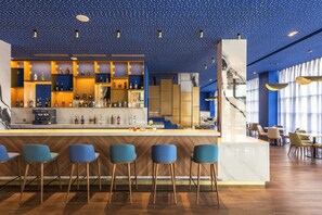 A modern bar area with a marble countertop, blue bar stools, and a ceiling with a starry pattern.
