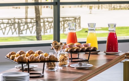 A breakfast buffet with pastries and drinks, overlooking a beach and ocean view.
