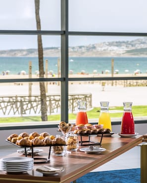 A breakfast buffet with pastries and drinks, overlooking a beach and ocean view. - Barcelo Tanger (Tangier)