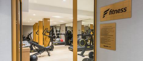 A gym with exercise equipment, a wooden floor, and a sign that says "fitness".