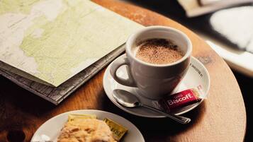 A table with a cup of coffee, a biscuit, a map, and a book.