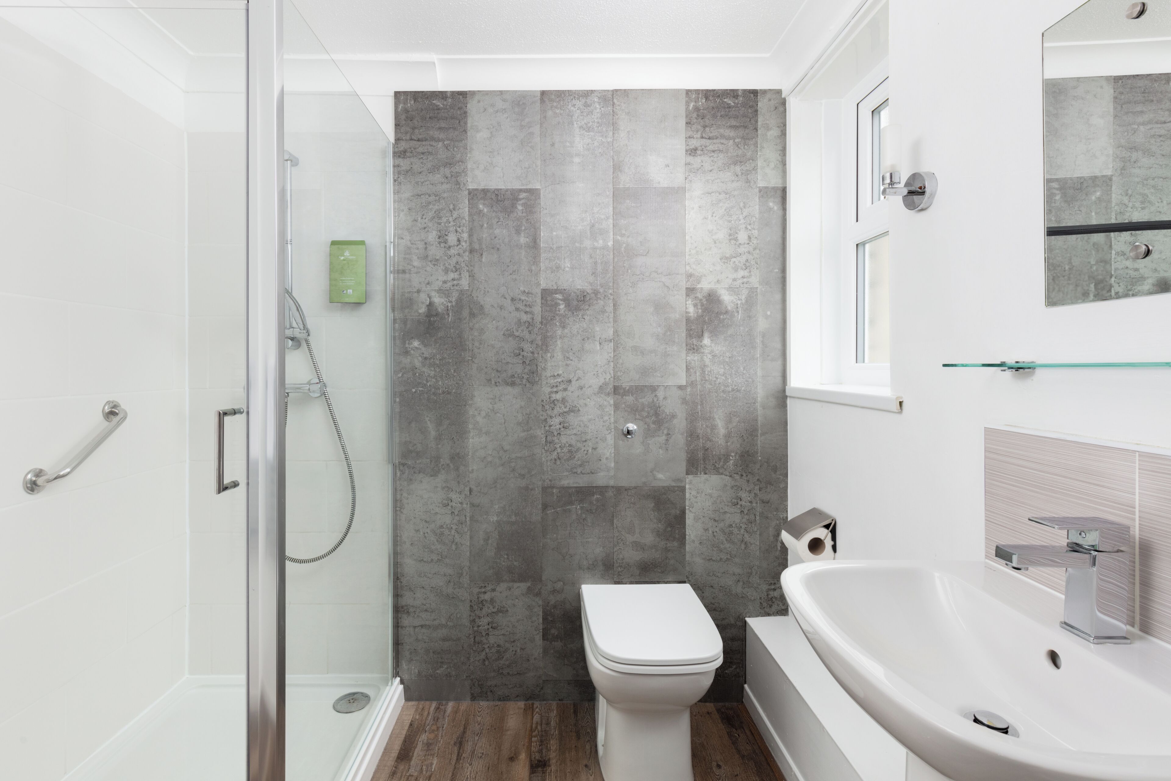 Un baño moderno con cabina de ducha de vidrio, un inodoro blanco y un lavabo grande.