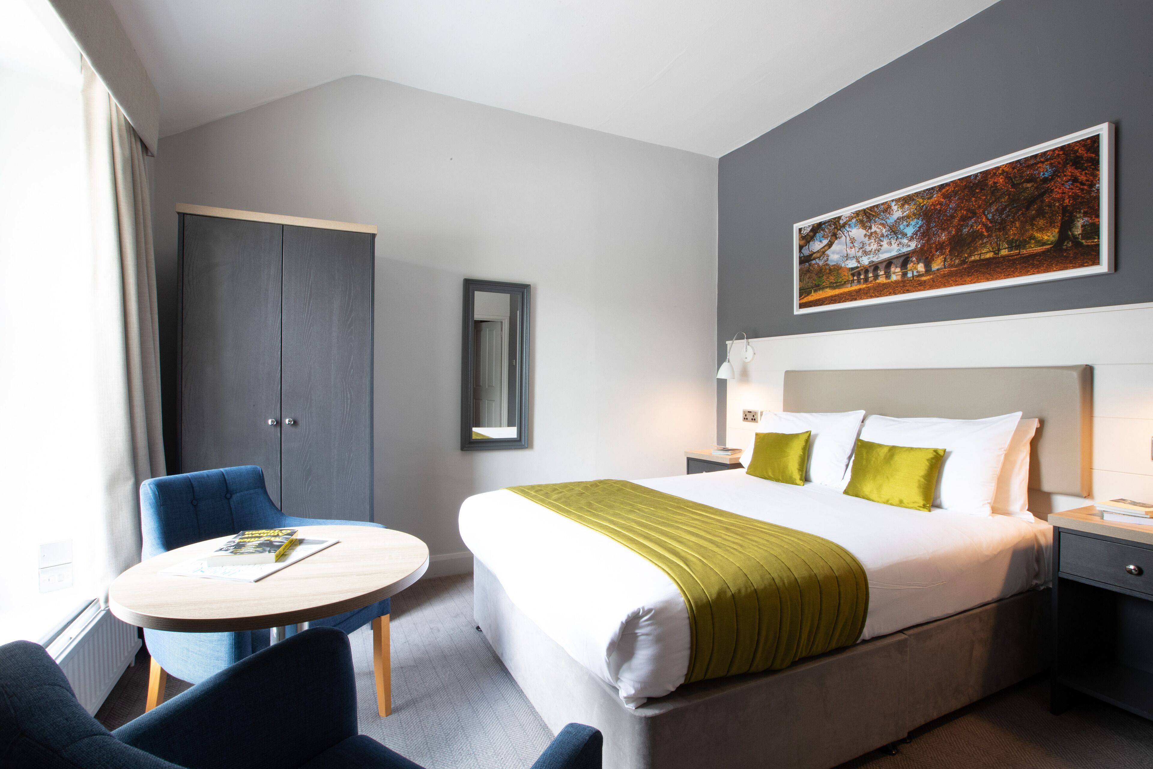 Une chambre d’hôtel comprenant un lit, une table de chevet, une lampe et une table ronde avec des chaises.