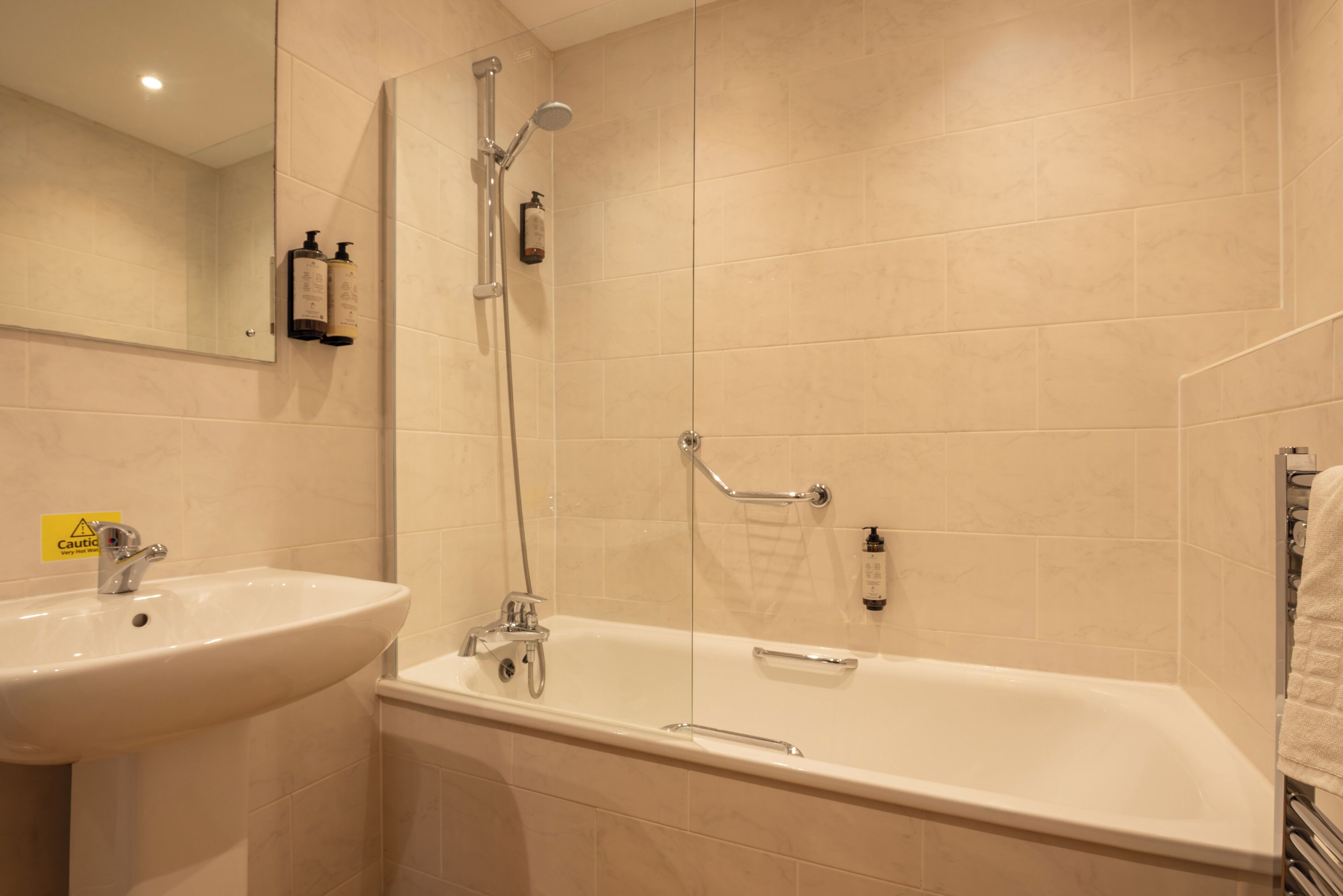 A bathroom with a sink, mirror, shower, and bathtub.