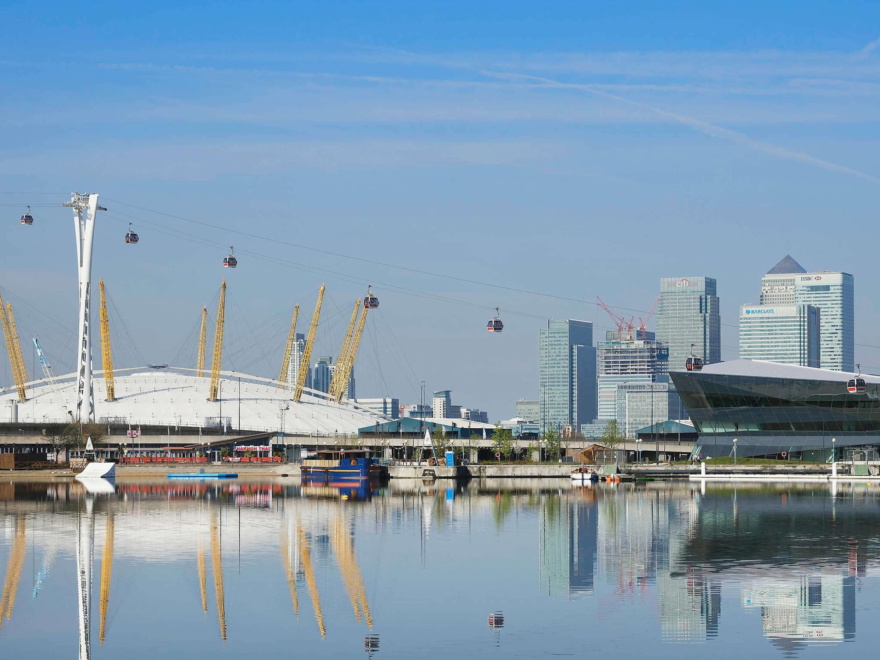 A waterfront view with a modern stadium, a bridge, and high-rise buildings in the background.
