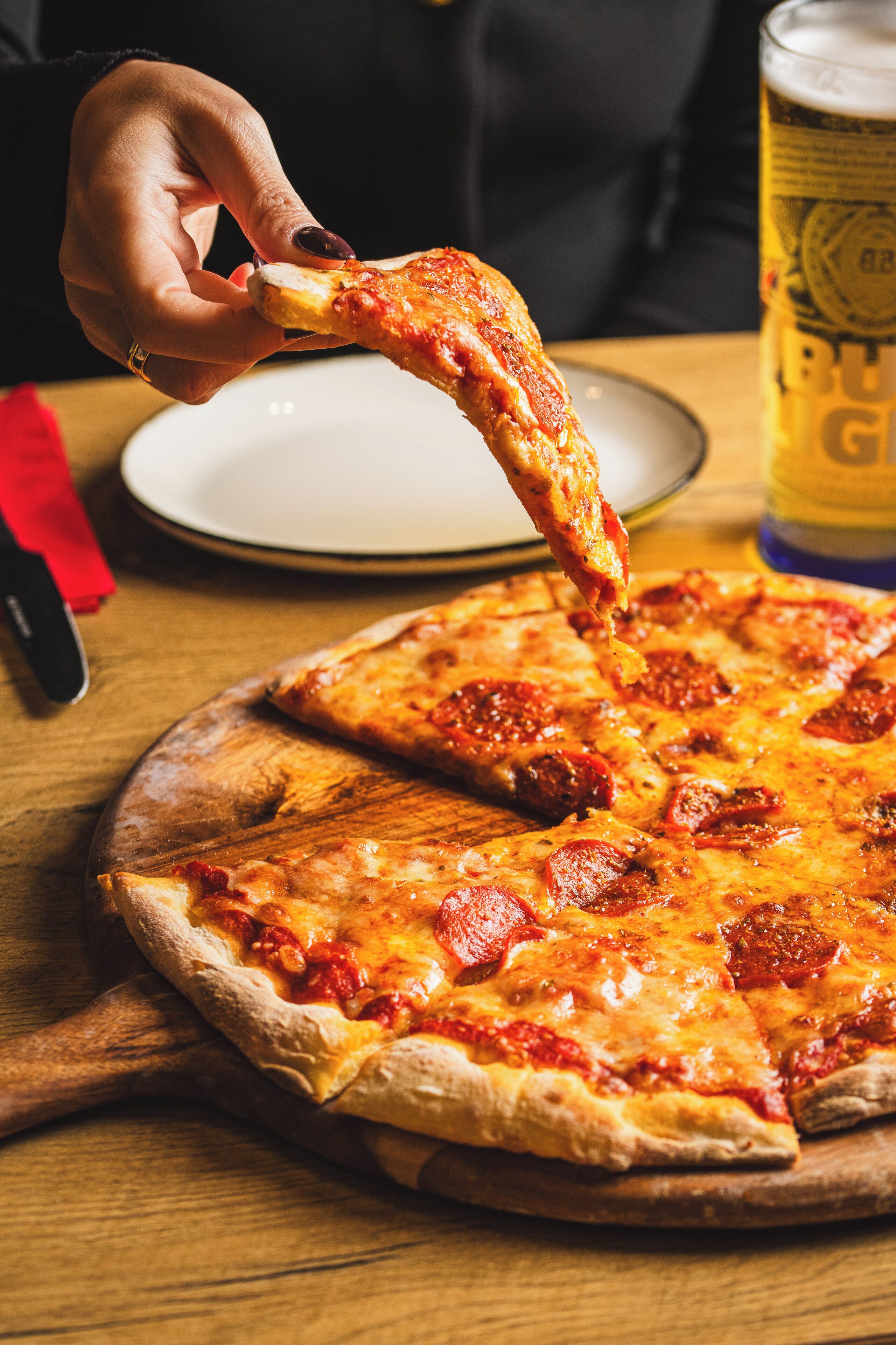 Pizza sobre un tauler de fusta, amb una fetxa aixecant-se.