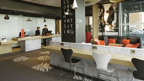 Zona de recepción moderna con mostrador, asientos y una columna grande con texto.