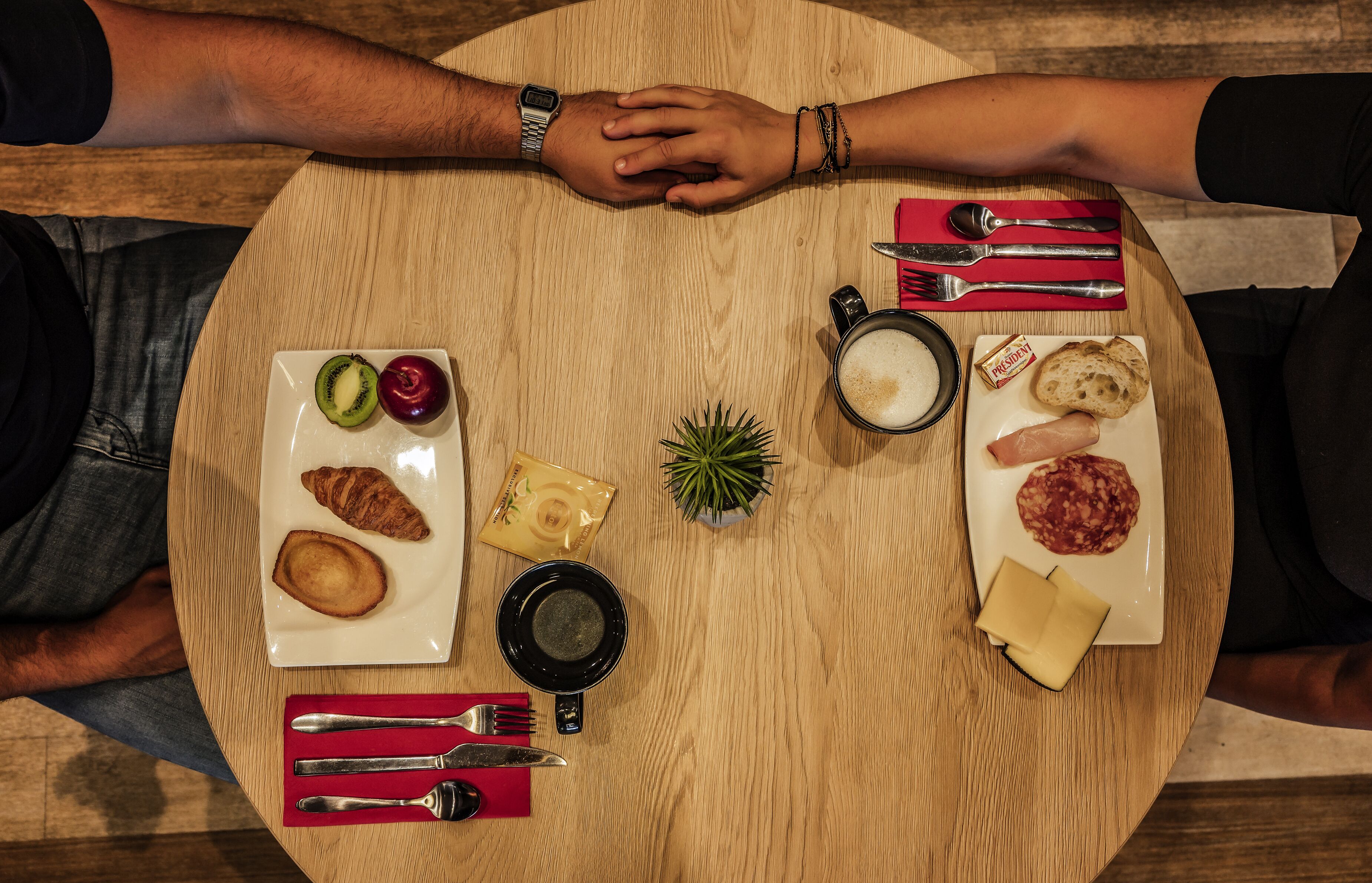 A round wooden table with a variety of food items and utensils.