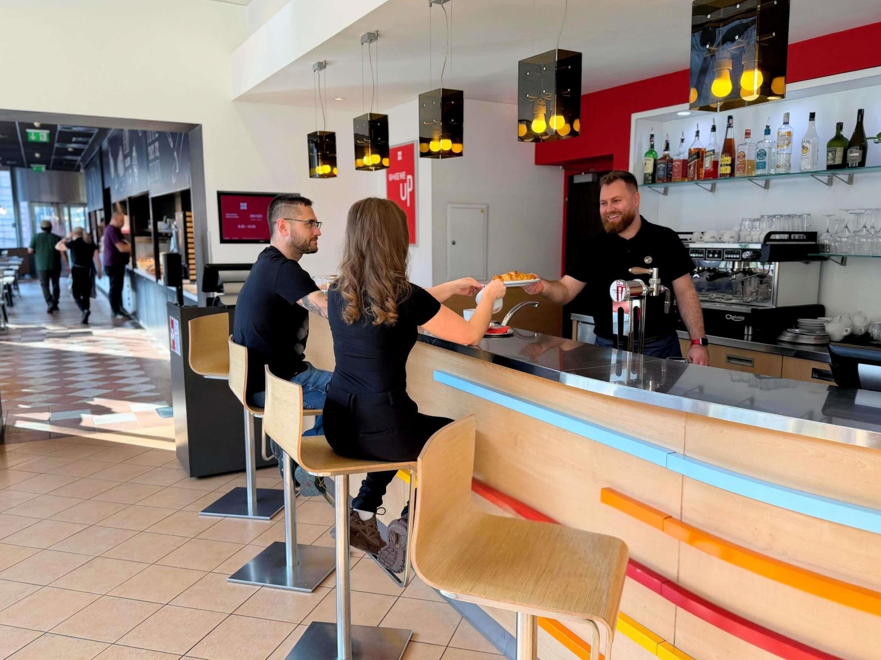A bar area with stools, a counter, and a variety of bottles on shelves.