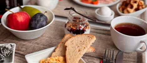 A breakfast tray with toast, scrambled eggs, a bowl of fruit, a cup of coffee, and a plate with ham and cheese.