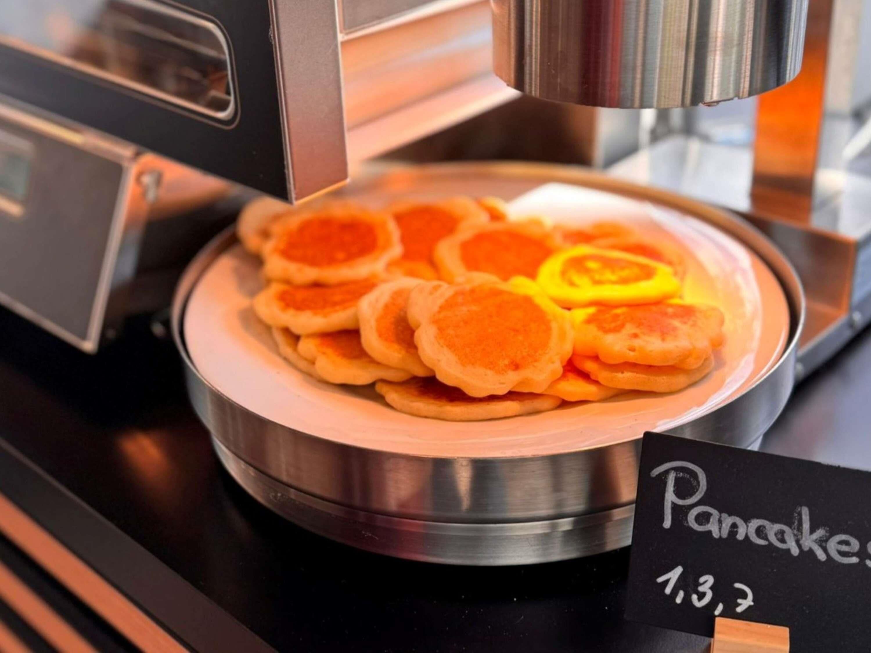 A stack of pancakes on a metal plate with a sign indicating the price.