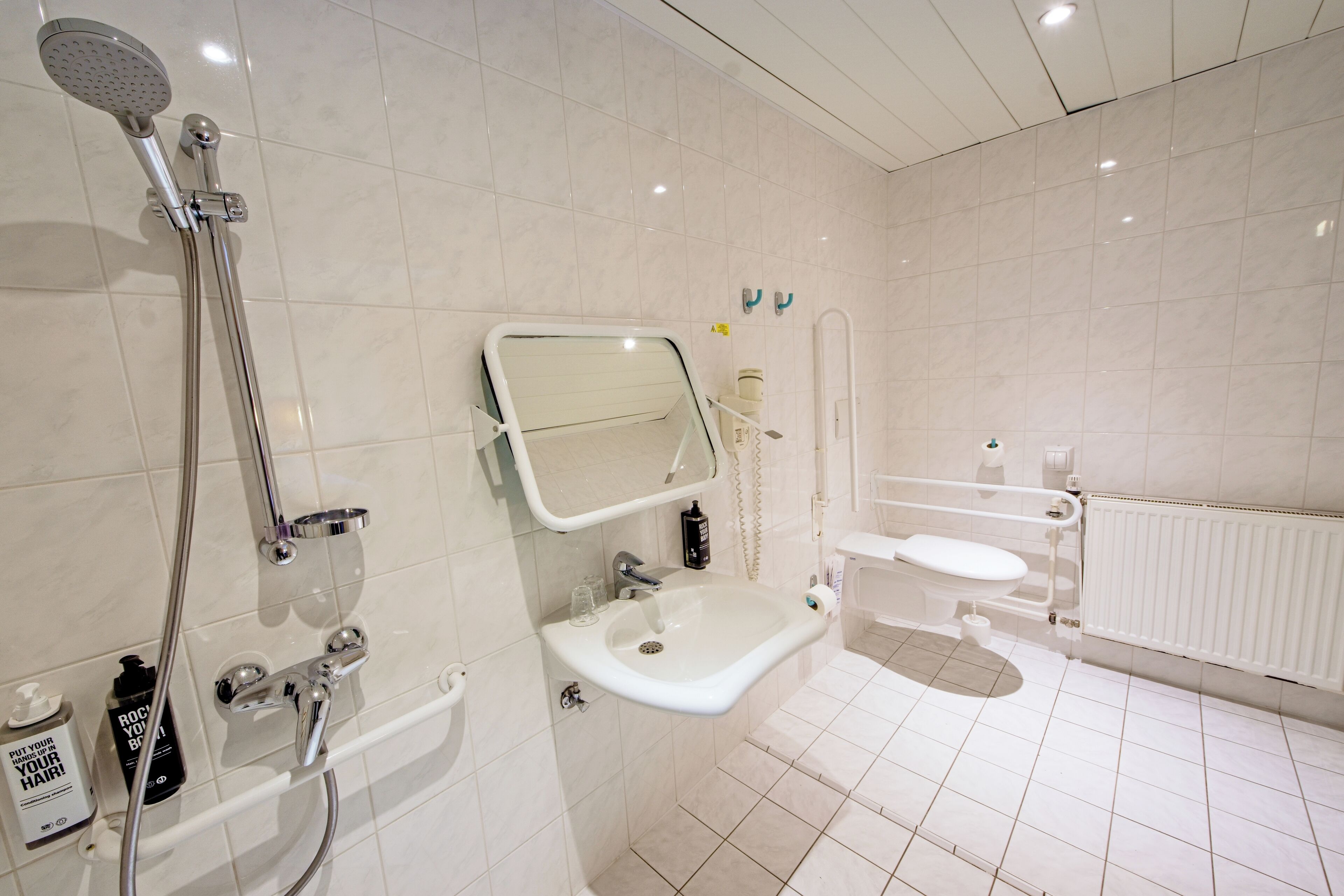 A modern bathroom with a shower, sink, toilet, and a mirror.