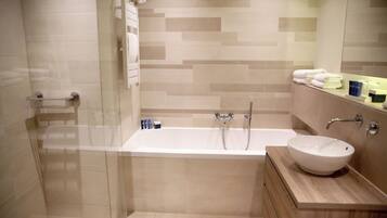 A modern bathroom with a glass-enclosed shower, a freestanding bathtub, and a wooden vanity with a white sink.