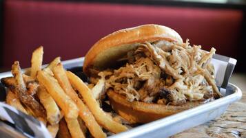 A pulled pork sandwich with fries on a tray.