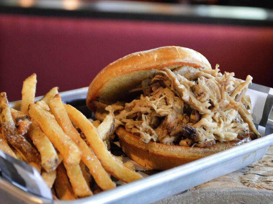 A pulled pork sandwich with fries on a tray.