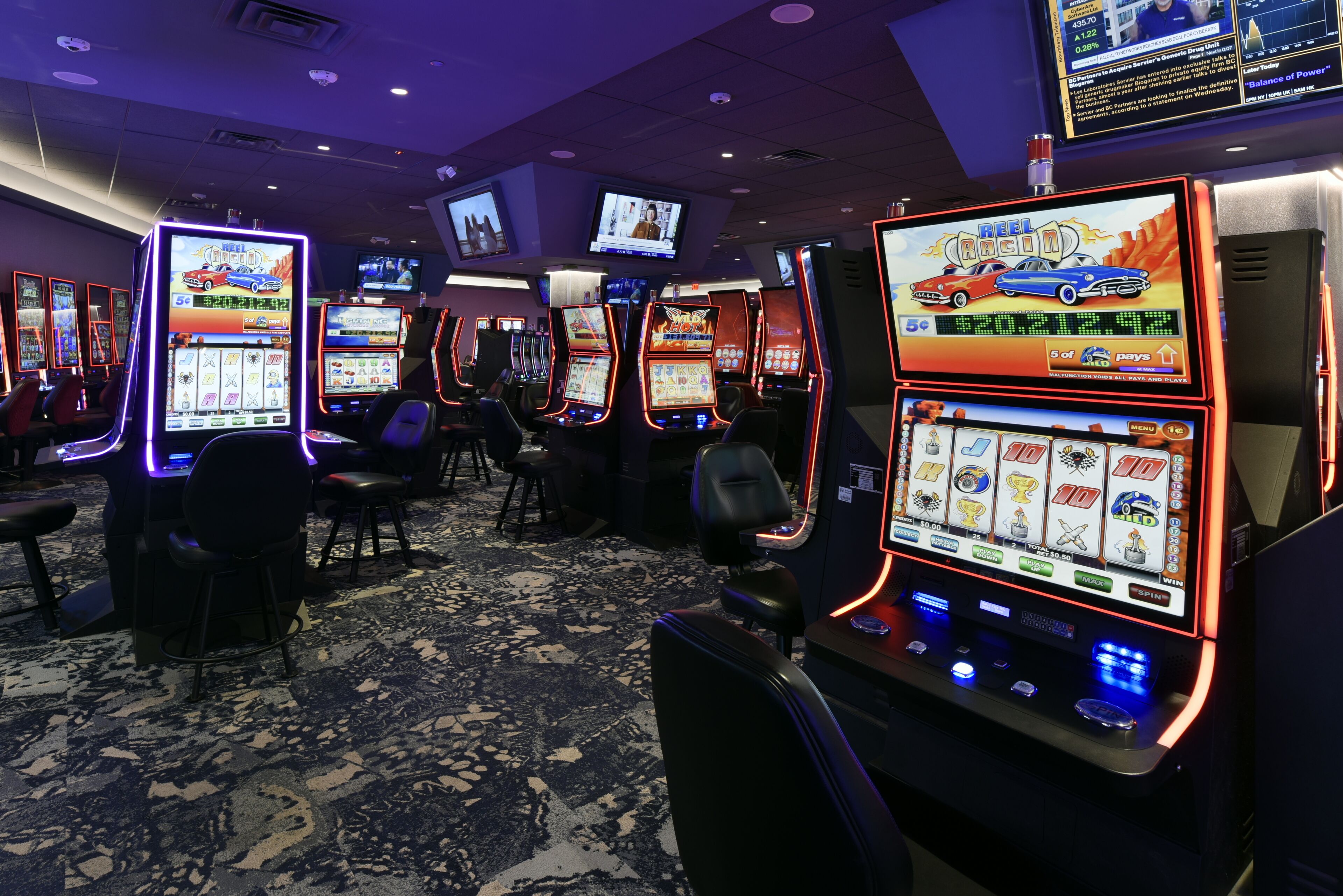 A casino with multiple slot machines and a carpeted floor.