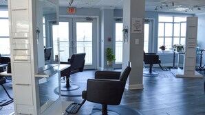 A modern salon with multiple black salon chairs, a white reception desk, and large windows allowing natural light. - Rod 'N' Reel Resort (Chesapeake Beach)