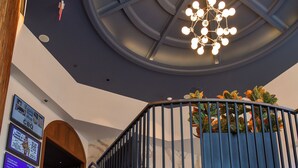 A staircase with a wooden handrail, a blue wall, and a ceiling light fixture. - Rod 'N' Reel Resort (Chesapeake Beach)