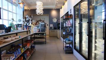 A store interior with shelves stocked with various products, a trash bin, and a refrigerator displaying packaged goods.