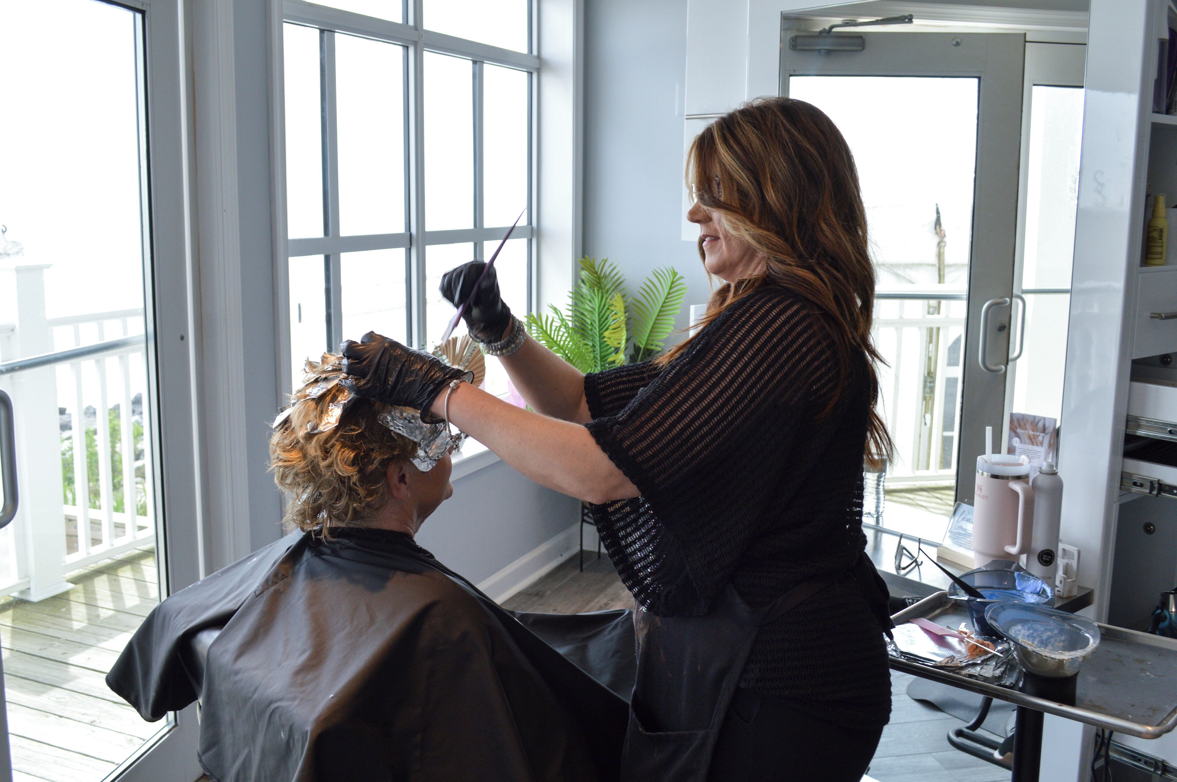 A salon interior with a large window, a plant, and salon equipment.
