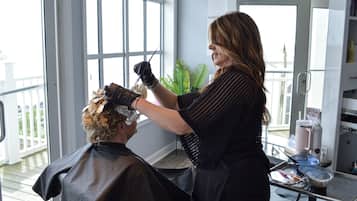 A salon interior with a large window, a plant, and salon equipment.