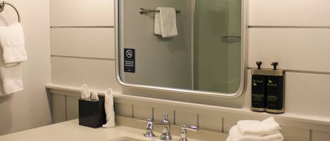 A hotel bathroom with a large mirror, two sinks, and a towel rack.