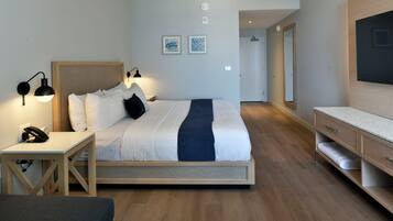 A modern hotel room with a bed, bedside table, lamp, and a flat-screen TV.