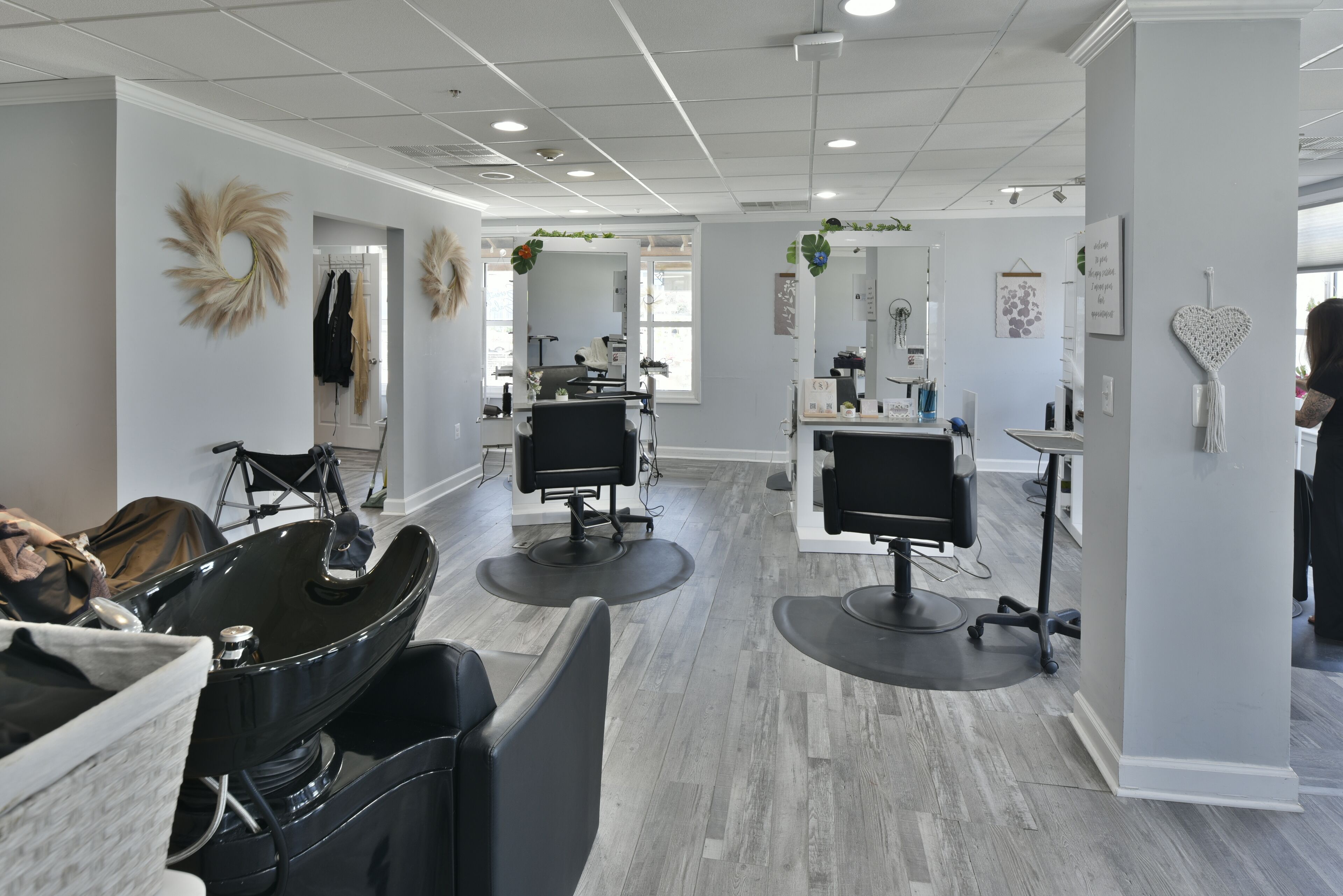 A modern hair salon with three chairs, a large mirror, and a reception area.