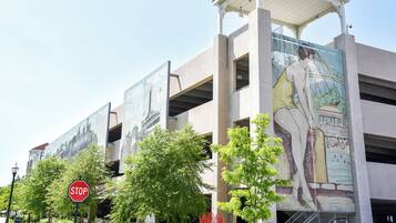 A building with a mural of a woman and a stop sign in front.