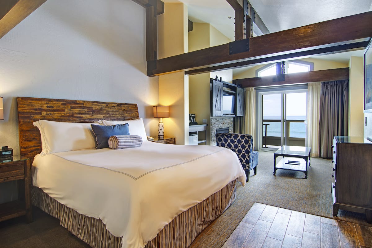 A spacious bedroom with a large bed, a wooden headboard, a desk, and a view of the outdoors.