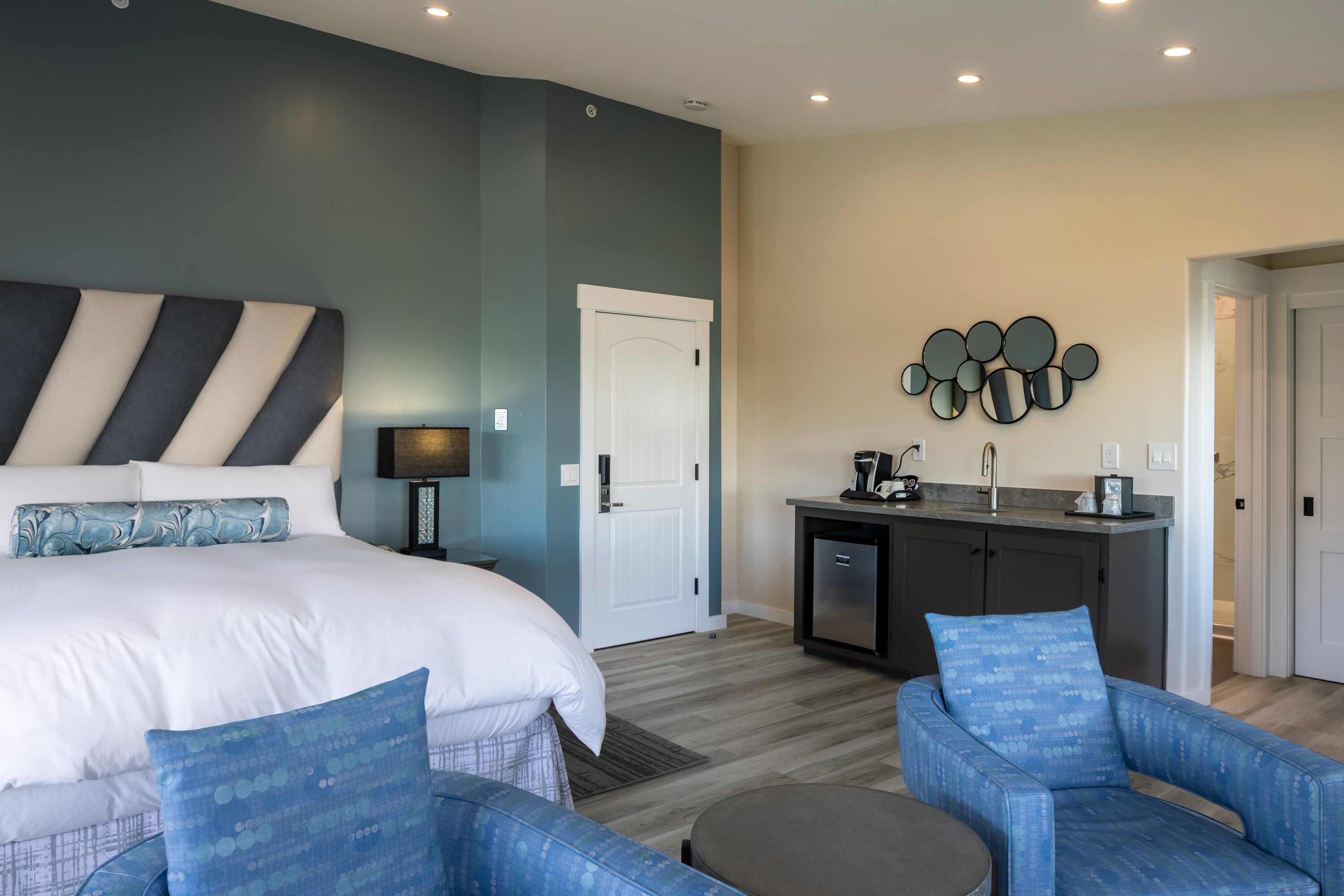 A modern hotel room with a large bed, a desk, and a seating area.
