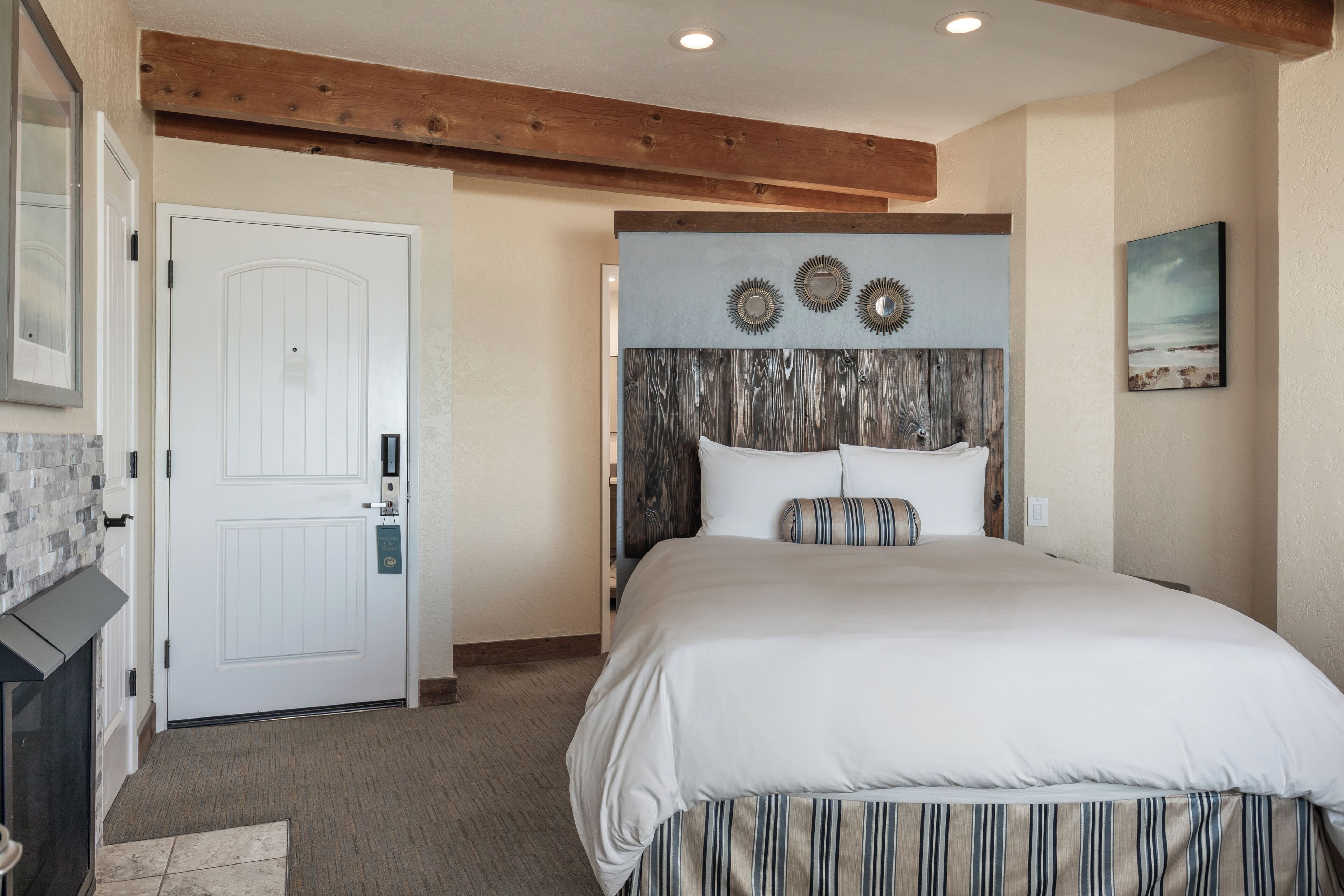 Une chambre à coucher avec une tête de lit en bois, une porte blanche et un tableau encadré accroché au mur.