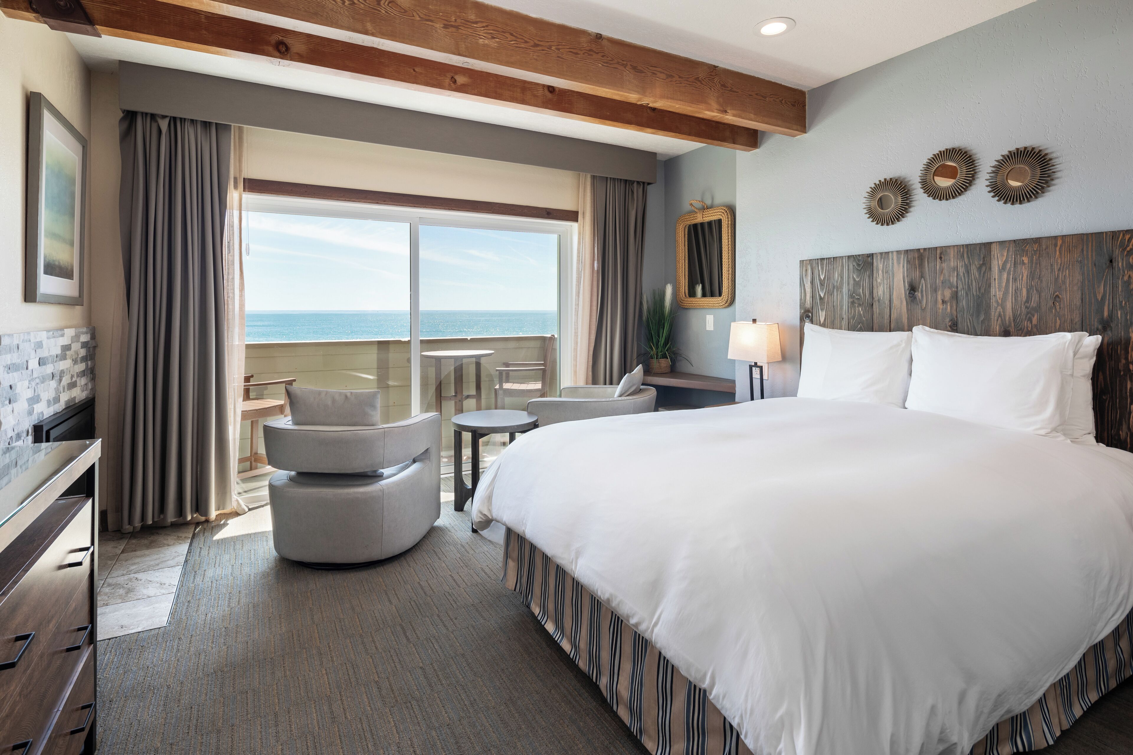A hotel room with a large bed, a desk, a chair, and a view of the ocean.
