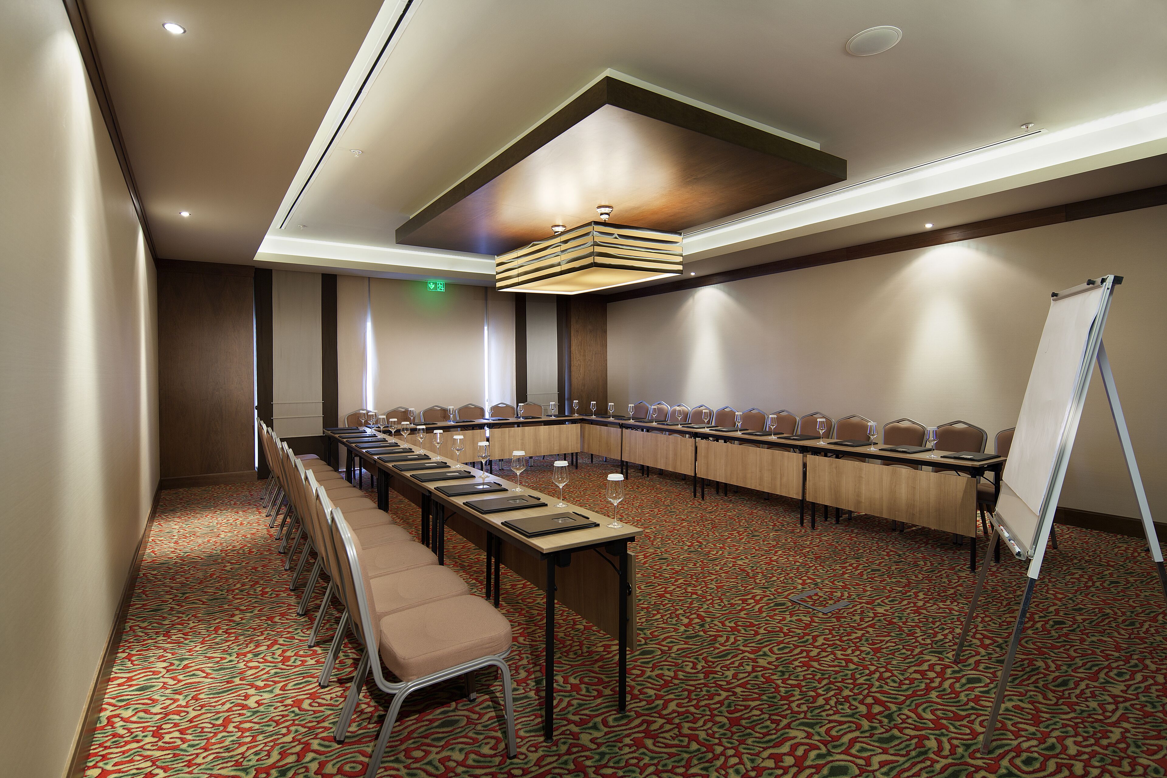 A conference room with a long table, chairs, a whiteboard, and a carpeted floor.