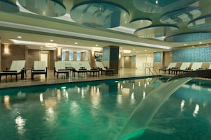 Un área de piscina interior moderna con sillones de descanso y un tobogán de agua.