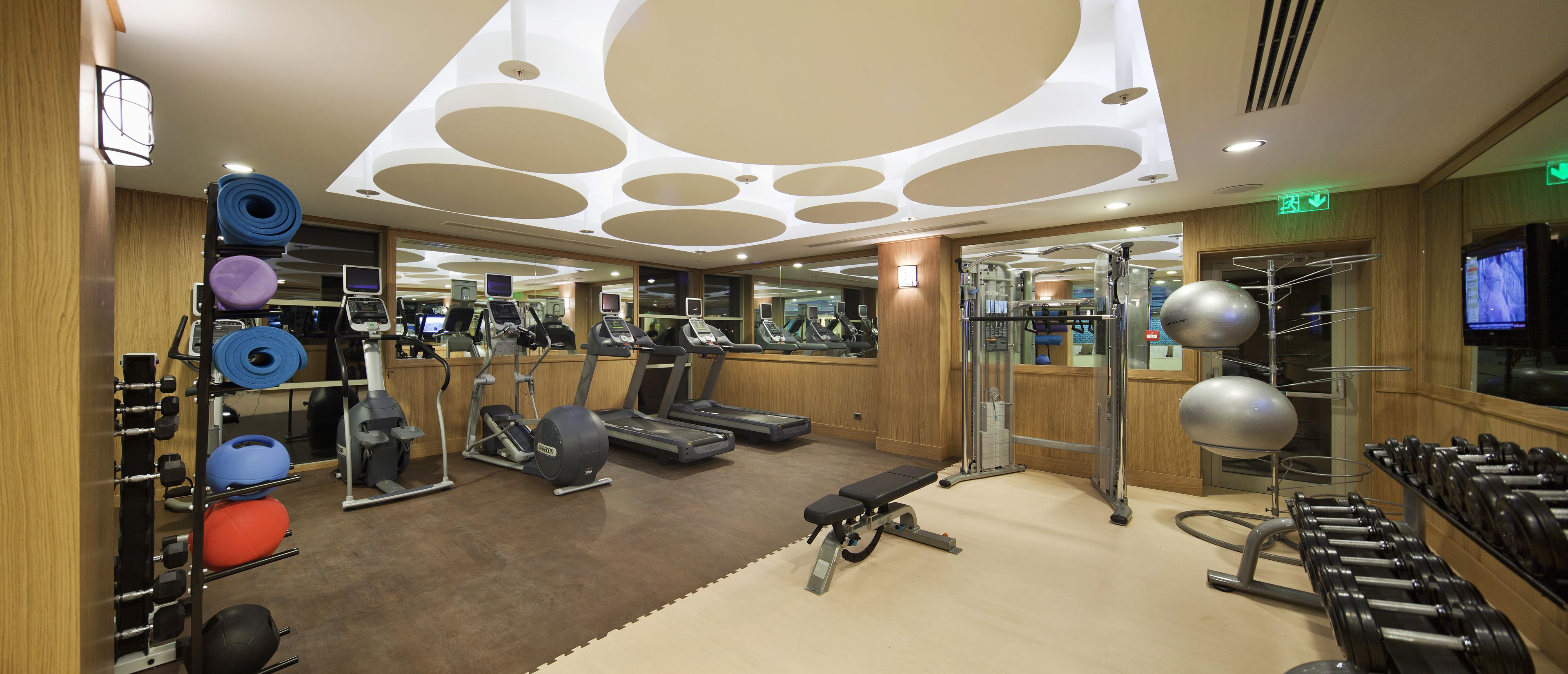 A gym with cardio machines, weightlifting equipment, and a mirrored wall.