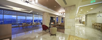 Un hall amplio con chimenea, asientos cómodos y ventanas grandes que ofrecen vista a la ciudad.