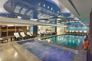 Una piscina techada, una piscina al aire libre, sombrillas