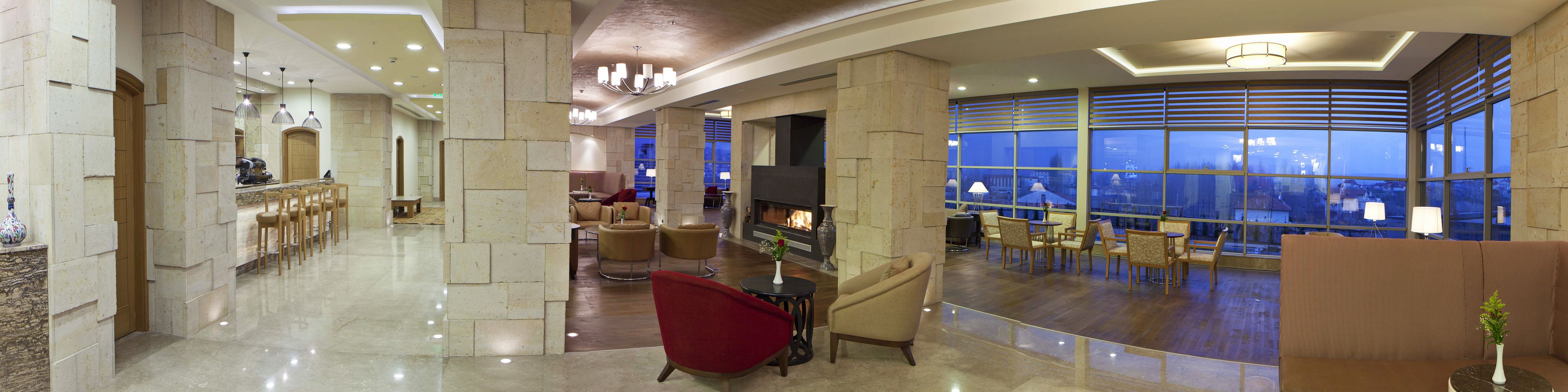 En rummelig lobby med et moderne design, der inkluderer et barområde, siddepladser og et stort vindue med udsigt over byen.