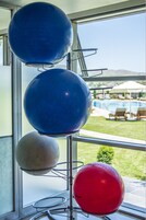 Pelotas de ejercicio en un soporte junto a una ventana con vistas a una zona de piscina.