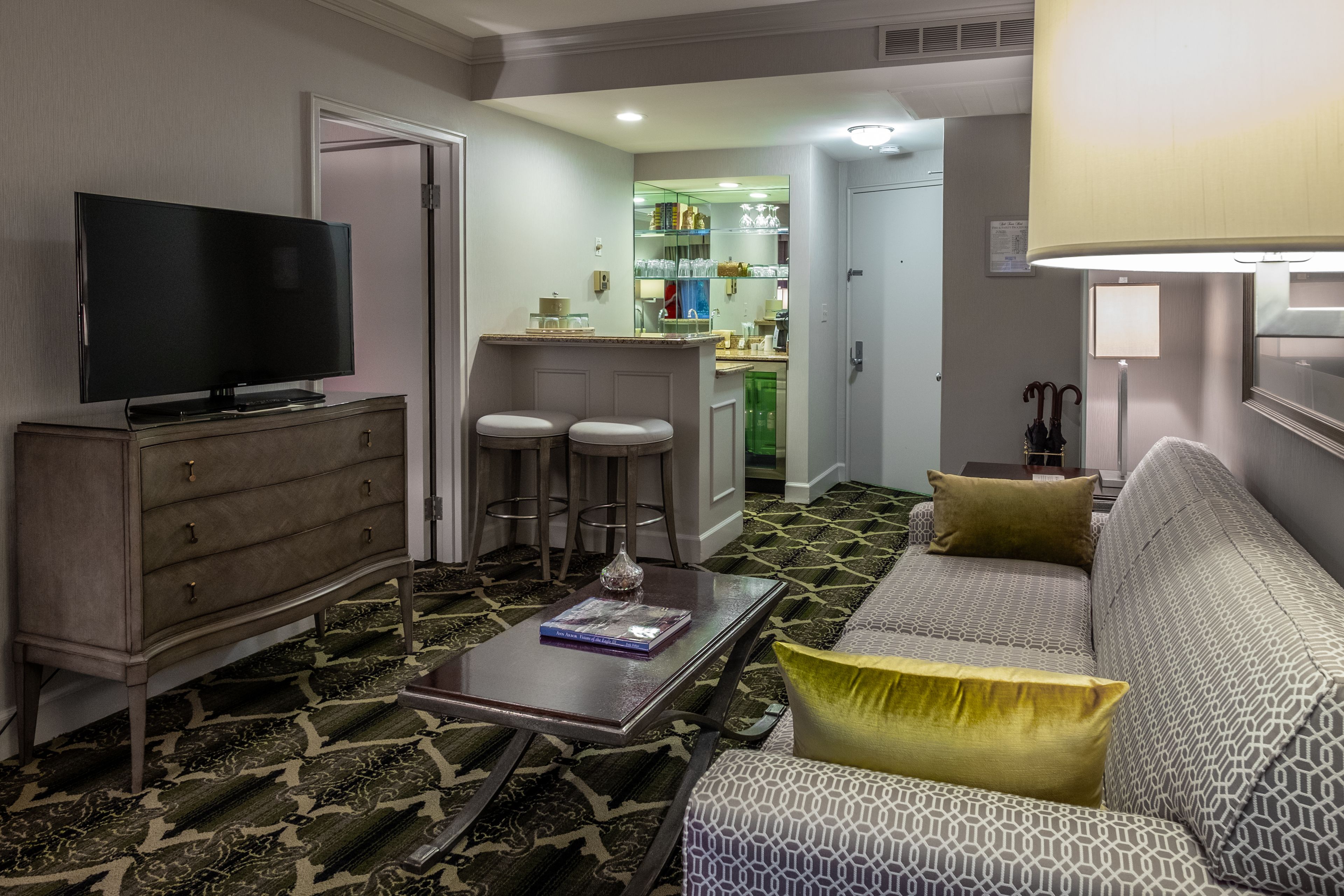 A living room with a TV, a sofa, a coffee table, and a patterned carpet.