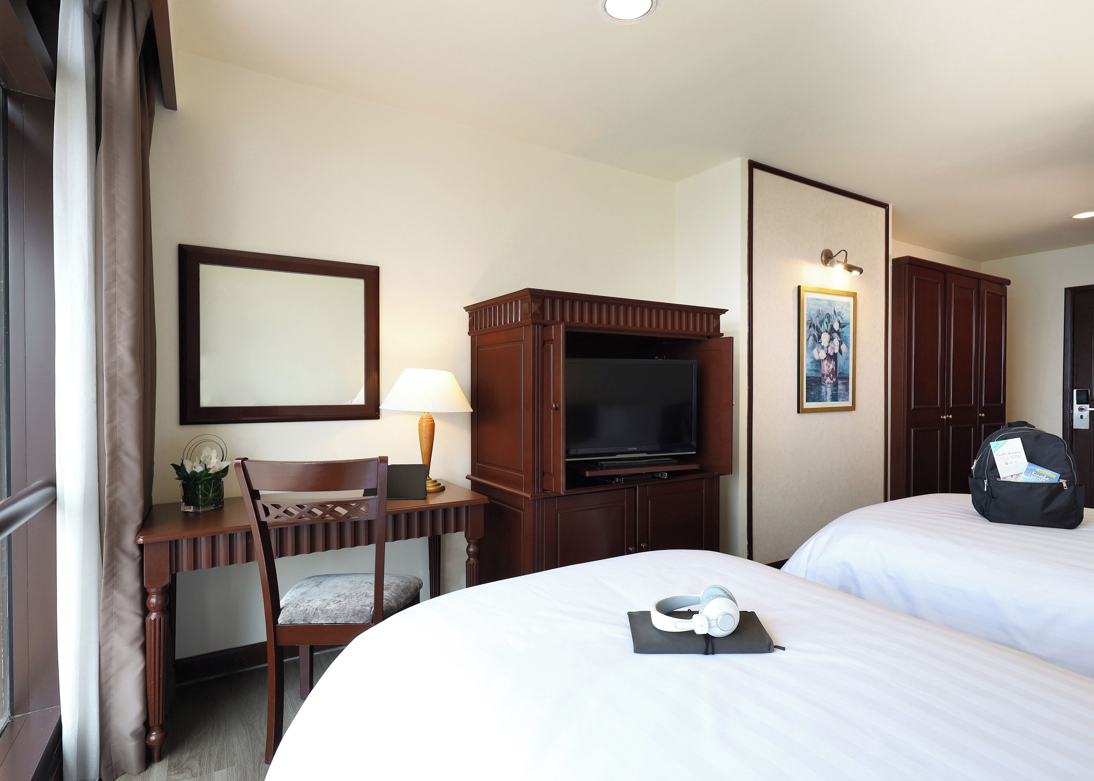 Una habitación de hotel con una cama, un escritorio con lámpara, un televisor y un armario.