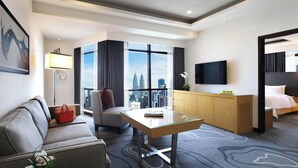 A modern hotel room with a sofa, armchair, desk, and bed.