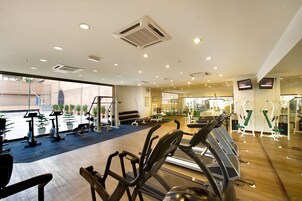 A gym with cardio equipment, weight machines, and a mirrored wall.