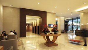 A modern lobby with a polished floor, a reception desk, and a seating area.