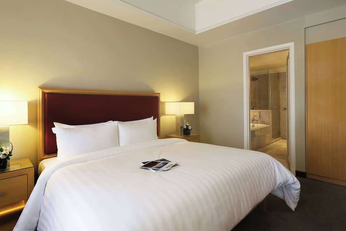 Une chambre d’hôtel avec un grand lit, deux lampes de chevet, une table de chevet et une armoire en bois.