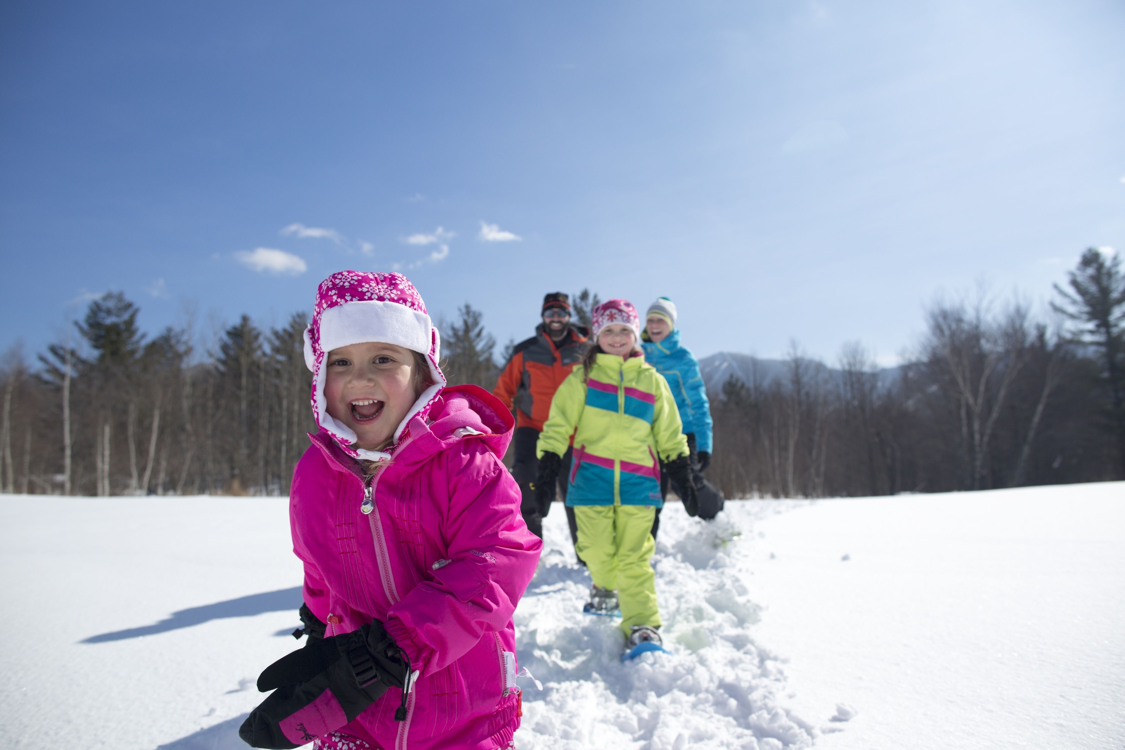 A group of people in winter clothing walking on snow-covered ground.