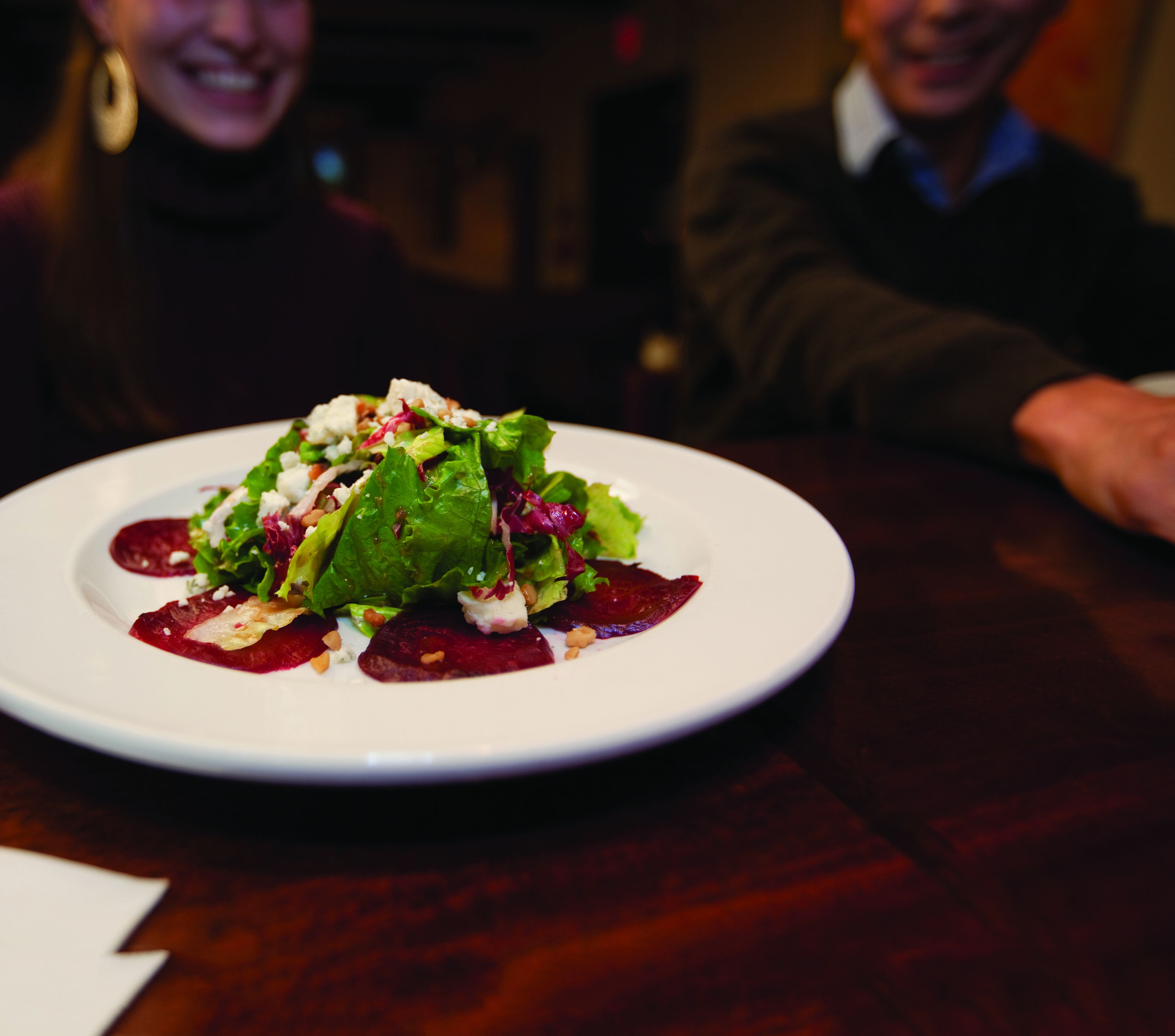 Une assiette de nourriture comprenant une salade, des betteraves et du fromage, le tout présenté sur une assiette blanche.